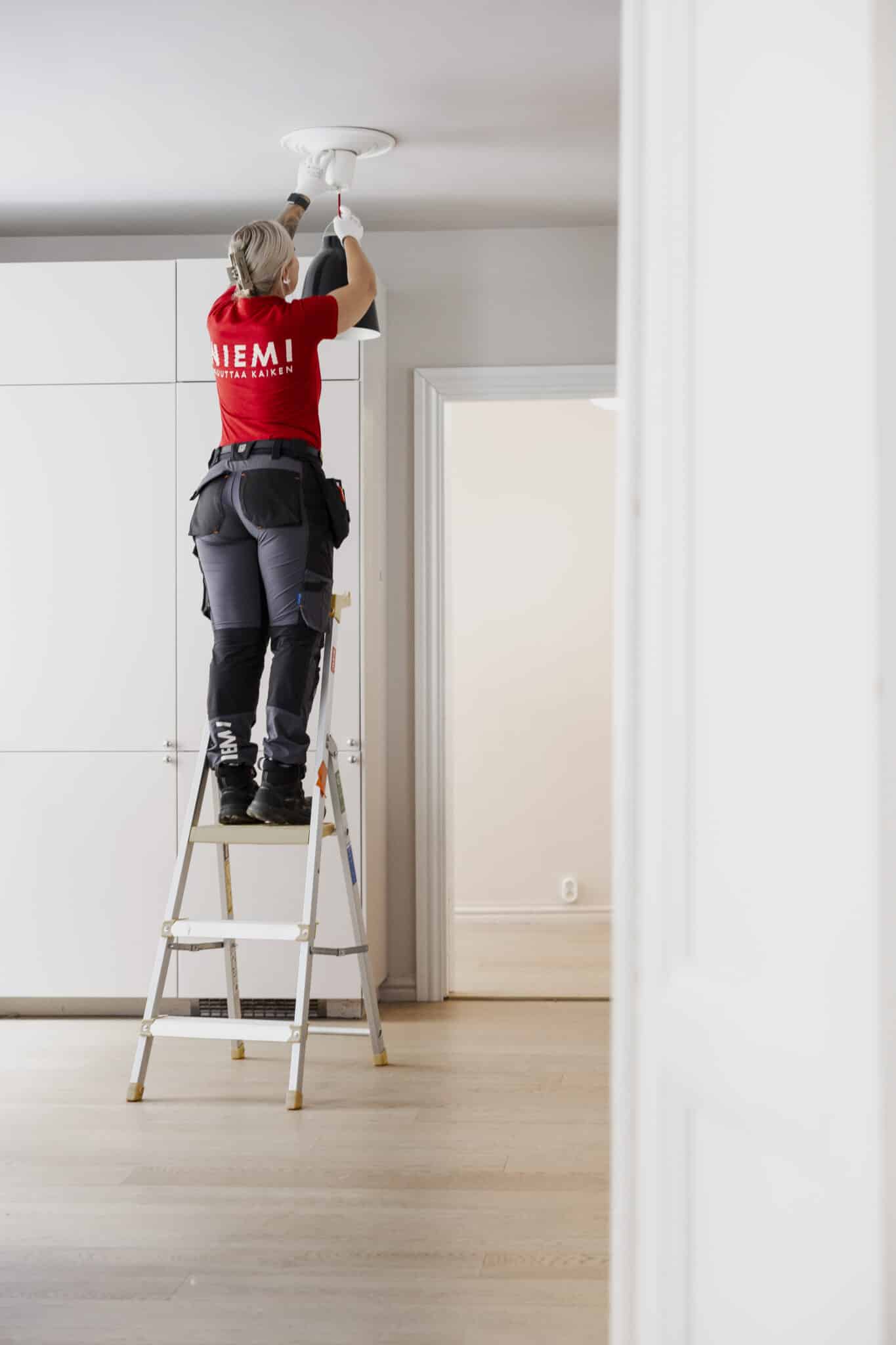 Muuttaja asentaa lamppua kattoon