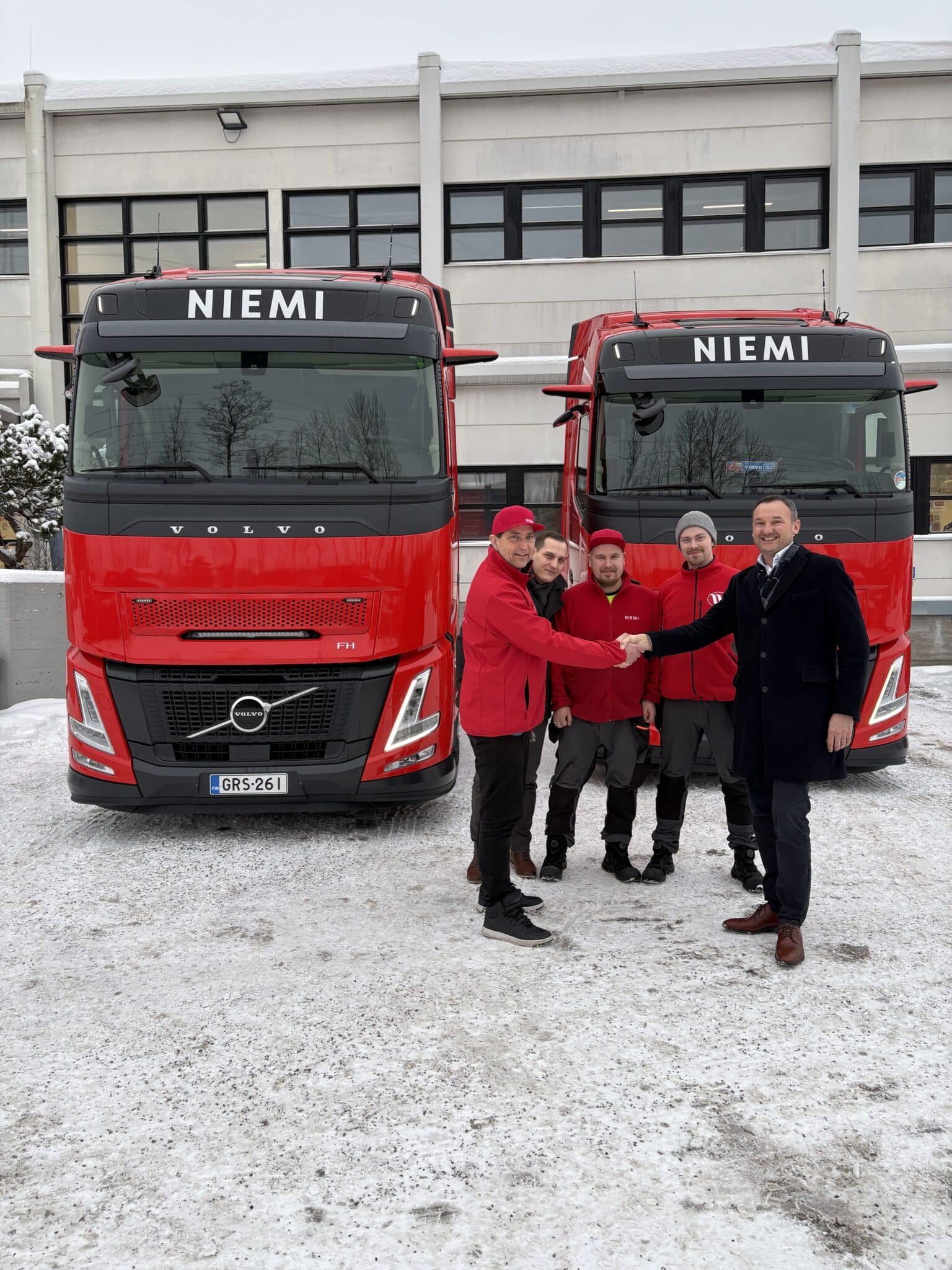Kuvassa uudet rekkaveturit Niemen toimipisteen edessä. Toimitusjohtajat kättelevät.